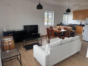 a living room with a white couch and a kitchen at Entre Mar e Vinhas RRAL Nº5668 in Biscoitos