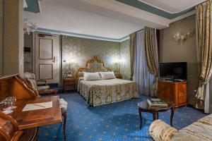 
a hotel room with a bed, chair, table and lamps at Al Ponte Antico in Venice
