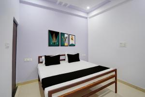 a white room with a bed with black pillows at Hotel O AVS Inn in Bheta