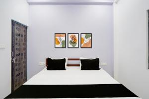 a bedroom with a white bed with four pictures on the wall at Hotel O AVS Inn in Bheta