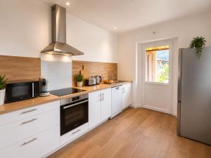 a kitchen with white cabinets and a stainless steel refrigerator at La Maison du Clain in Jaunay-Clan