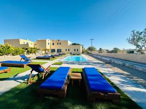 a swimming pool with blue chaise lounges next to a building at Irigeneia Hotel in Perissa +37 photos