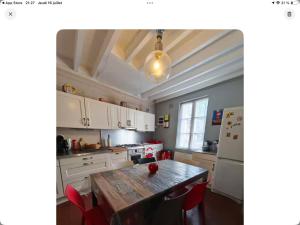 a kitchen with a wooden table and red chairs at Le nid marin in Étretat