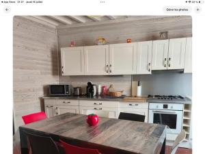 a kitchen with white cabinets and a wooden table at Le nid marin in Étretat +8 photos