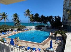 a view of a swimming pool with palm trees and the ocean at KASA Emmas Ocean View in San Juan