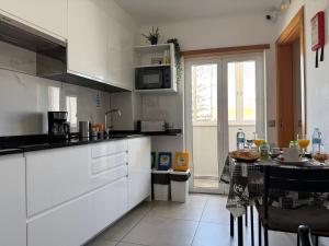 a kitchen with white cabinets and a table in it at LC's Guesthouse in Lagos