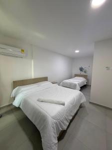 a bedroom with two beds with white sheets at Hotel Boutique Trinitarias in Valledupar