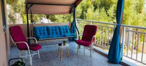 a balcony with a blue couch and two chairs at Joan's House in Nea Potidaea