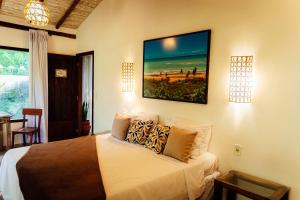 a bedroom with a bed with a painting on the wall at Pariri Suites in Trancoso