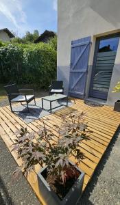 a wooden deck with two chairs and a potted plant at Chambre privé climatisé in Vertaizon +8 photos