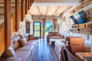 a living room with leather couches and a tv at VILA K3 Komarnica in Šavnik