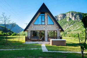 a small house with a black roof on a green field at VILA K3 Komarnica in Šavnik