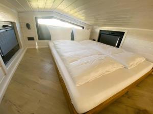 a large white bed in a small room with a window at Tiny House WICA in Königs Wusterhausen