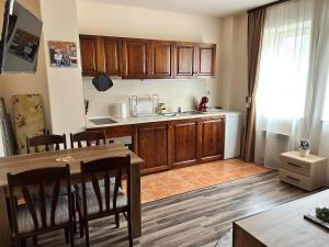 a kitchen with wooden cabinets and a table with chairs at Central apartment in Razlog