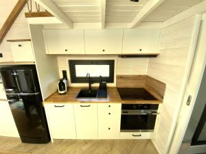 a kitchen with white cabinets and a black refrigerator at Tiny House WICA in Königs Wusterhausen +6 photos