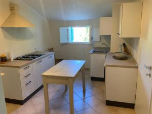 a kitchen with white cabinets and a table in it at Les Chandelles in San Menaio