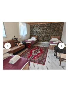 a living room with several beds and a stone wall at Old Rooms in Sheki