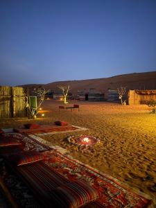 Ein Strand bei Nacht mit einem Teppich auf dem Sand in der Unterkunft Authentic Desert Camp - Al Wasil in Al Wāşil