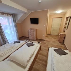 a room with three beds and a television in it at Pitvar Vendégház in Zalaegerszeg
