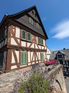 a house with green shutters on a stone wall at Pension bei Goscha mit Schlossblick in Braunfels