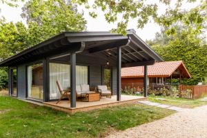 a house with a black roof and a deck at Bungalow Camping Los Manzanos in Santa Cruz de Oleiros