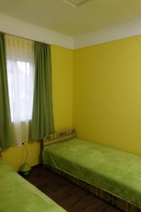2 camas en una habitación con paredes verdes y ventana en Mesteri Apartman 1A-B, en Mesteri