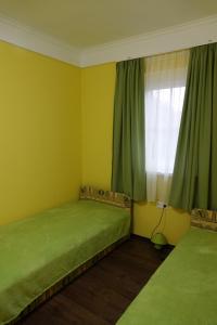 a bedroom with two beds and a window with green curtains at Mesteri Apartman 1A-B in Mesteri