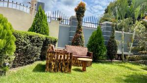 a garden with a bench and a chair in the grass at Murchison Close Motel in Masindi +3 photos