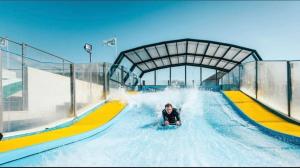 a man riding a wave ride in a water park at Beautiful 3 Bed Caravan with Views & Decking in Mortehoe