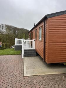 a house with a porch and a white fence at Beautiful 3 Bed Caravan with Views & Decking in Mortehoe