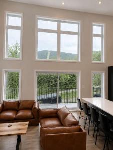 a living room with a couch and a table and windows at Spa Mountains & Ultimate Comfort - Le Jameson in Saint-Philémon