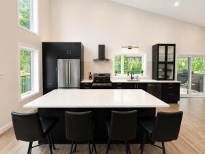 a kitchen with a large white island with black cabinets at Spa Mountains & Ultimate Comfort - Le Jameson in Saint-Philémon