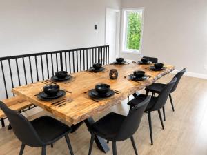 a wooden table with black chairs and a dining room at Spa Mountains & Ultimate Comfort - Le Jameson in Saint-Philémon +23 photos