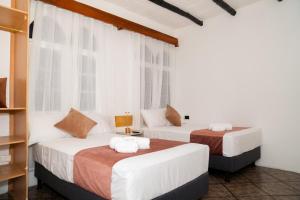 two beds in a room with two windows at Hotel Crossman in Puerto Ayora