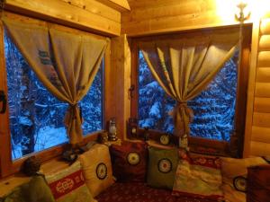 a living room with a couch and two windows at Chalet Baluma Maluba in Jahorina