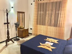 a bedroom with a bed with blue sheets and a fan at Domus Taprobana in Dankotuwa