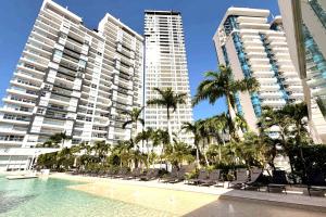a pool with chairs and palm trees and buildings at Playa Acapulco Espectacular Apartment in Acapulco