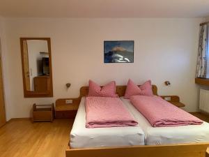 a bedroom with a bed with pink pillows on it at Berghaus Appartment in Biberwier