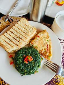 a plate of food with bread and greens on a table at Mansarda parkview Hotel in Nyagatare