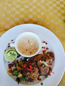 a plate of food with a bowl of soup and vegetables at Mansarda parkview Hotel in Nyagatare