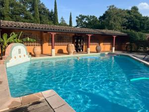 a large blue swimming pool in front of a building at L'Hacienda in Mialet