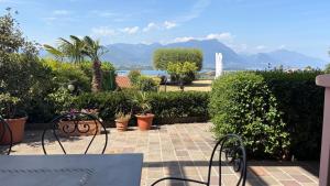 a patio with a table and chairs and plants at Flowers & garden apartment con vista lago in Manerba del Garda