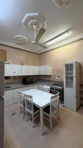 a kitchen with a white table and chairs in it at اجنحة رحال لشقق الفروشة in Medina