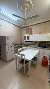 a kitchen with a white table and chairs and a refrigerator at اجنحة رحال لشقق الفروشة in Medina +19 photos