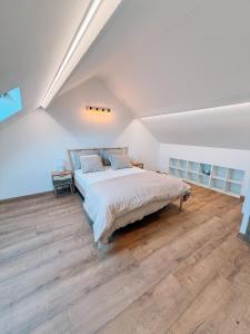 a white bedroom with a large bed and wooden floors at AirportHouse in Charleroi