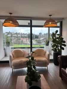 a living room with two chairs and large windows at The Roses in Puerto Varas