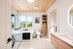 a bathroom with a tub and a toilet and a sink at Spa & Foosball - Le WKD in Saint-Philémon