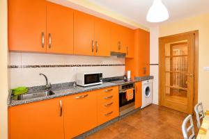 an orange kitchen with a sink and a microwave at Apartamento Mar de Carnota in San Mamede de Carnota
