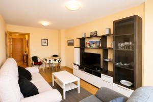 a living room with a white couch and a tv at Apartamento Mar de Carnota in San Mamede de Carnota