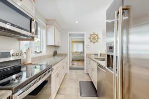 a kitchen with white cabinets and a stainless steel refrigerator at New Seabury Escape in Mashpee